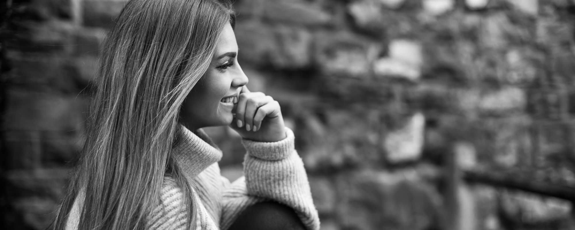 Frau sitzt mit angezogenem Knie vor einer Mauer – Portraitfotografie Soest